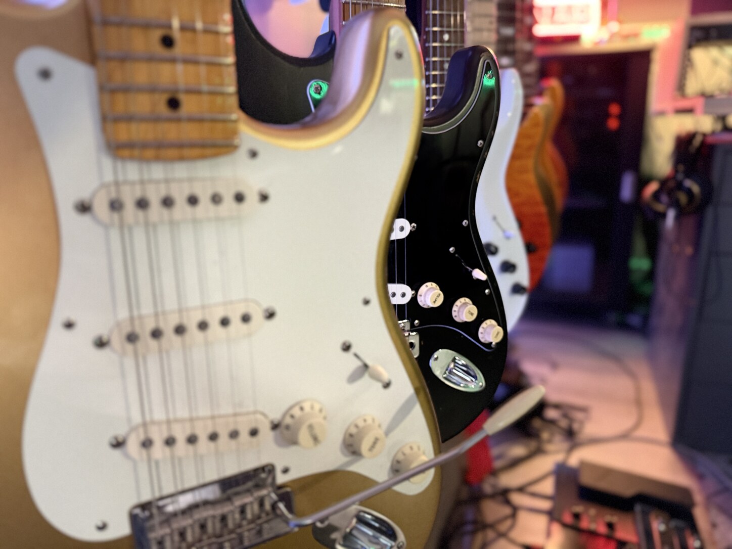 A row of electric guitars in Jamie Penner’s studio, photographed in warm coloured light